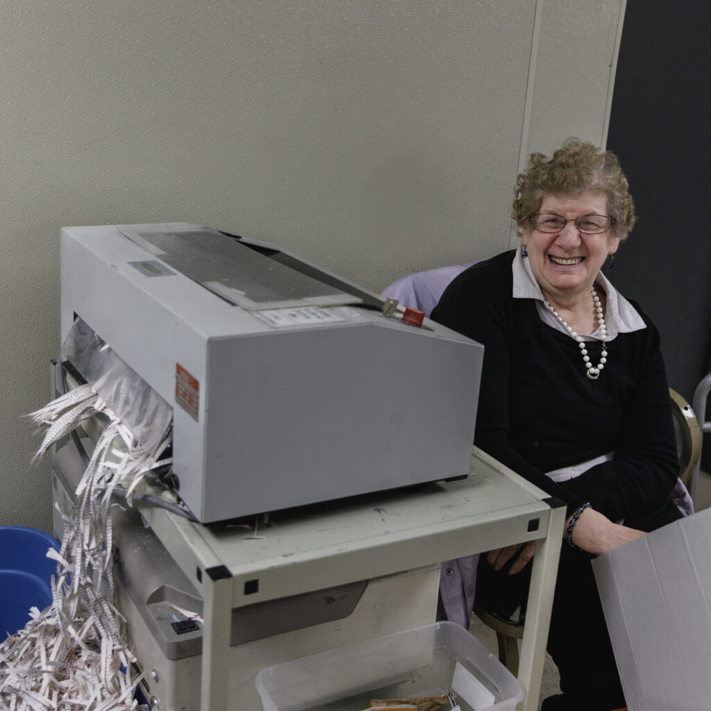 A woman sits next to a shredder at TVDSI's Day Center, which offers services for IDD in Greenleaf, KS.
